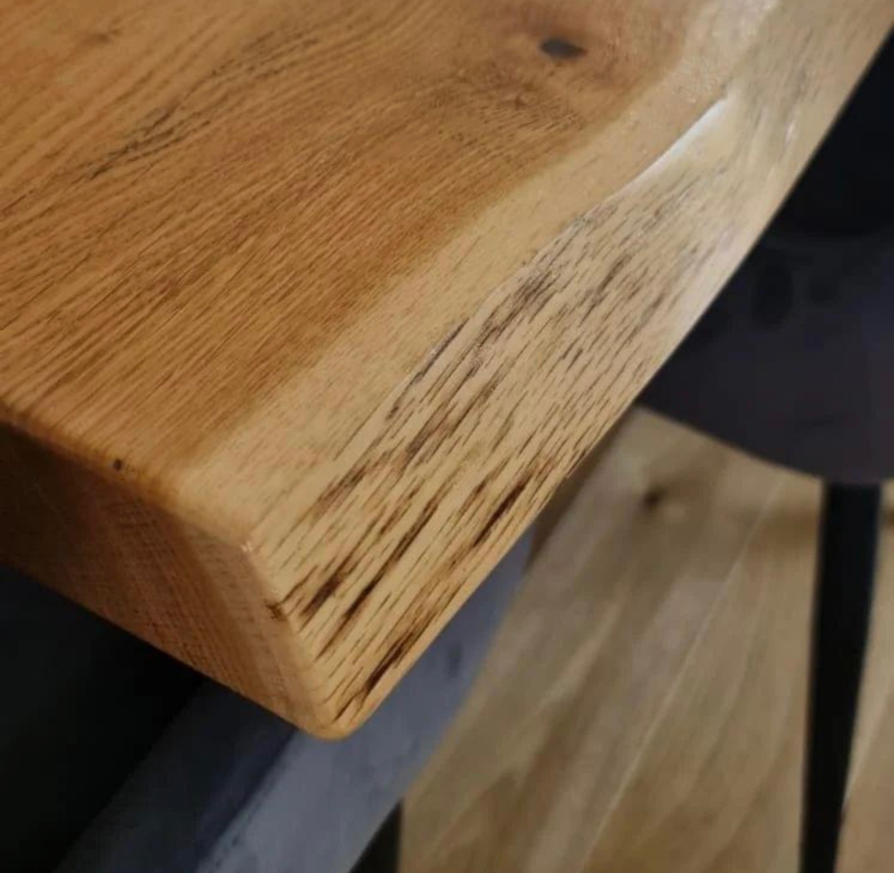 Blat stołu z litego drewna dębowego, z widocznym usłojeniem i naturalnymi krawędziami, osadzony na metalowej podstawie.