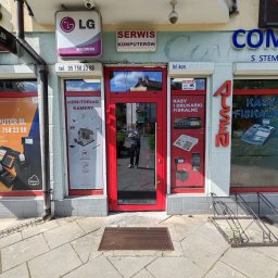 VINSTA SPÓŁKA CYWILNA WOJCIECH PAJĄK, DMYTRO ZHULINSKYI - Fasada lokalu usługowego z czerwonymi ramami okiennymi i drzwiowymi, oferującego serwis komputerowy, monitoring kamer oraz kasy i drukarki fiskalne, widoczny szyld LG Multimedia i kamery...