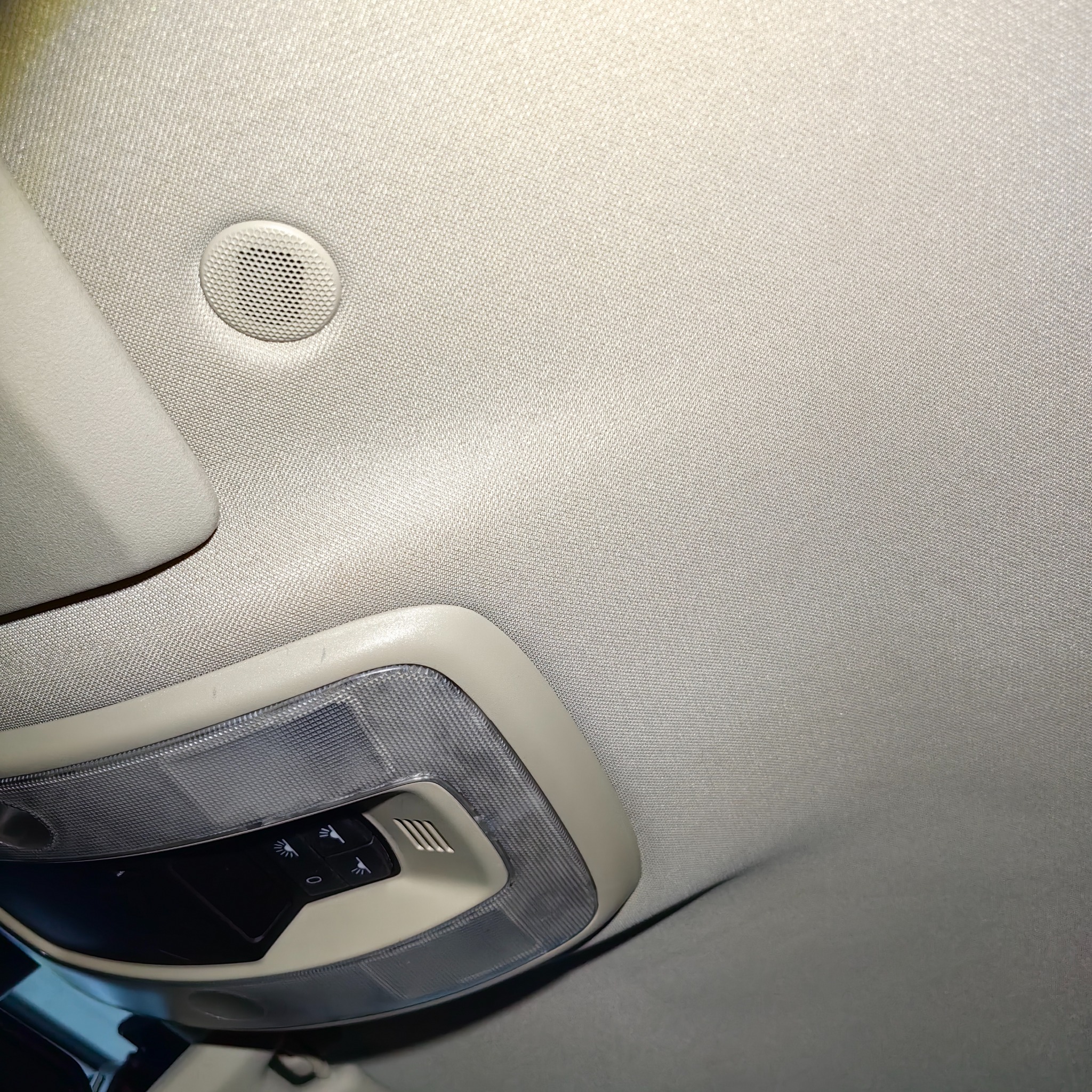 Wnętrze samochodu: beżowa podsufitka z lampką i głośnikiem, widok z dołu.