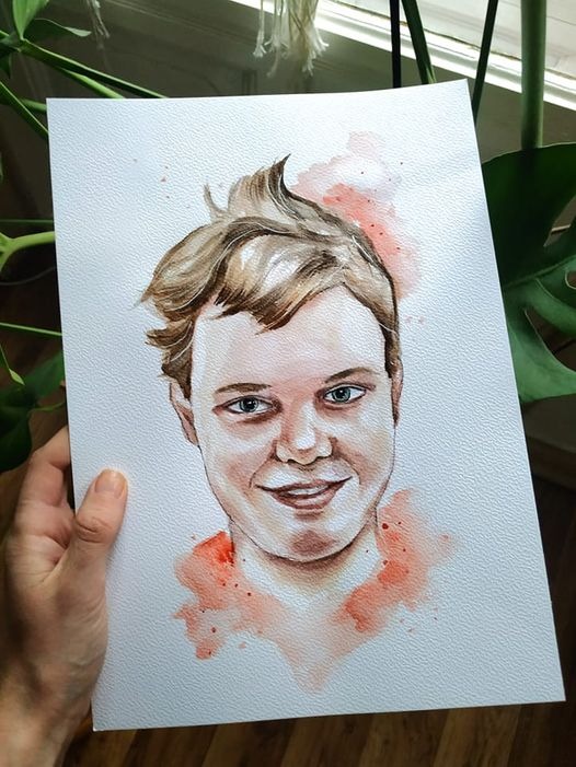 Portret akwarelowy młodego mężczyzny z blond włosami, trzymany w dłoni na tle roślin doniczkowych i okna.