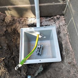 ELROI Robert Stankiewicz - Uziemienie: Żółto-zielony przewód uziemiający z zaciskiem w szarej skrzynce, umieszczonej w wykopie przy fundamencie budynku.