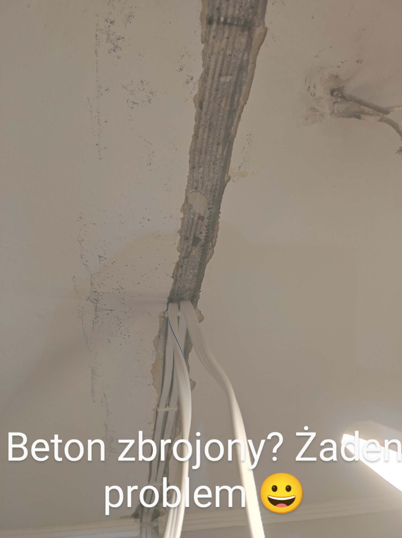 Bruzdowanie w suficie z betonu zbrojonego pod instalację elektryczną, widoczne przewody w białej izolacji.