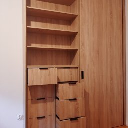 ATUMEBEL - Jasna, drewnopodobna szafa wnękowa z otwartymi półkami i wysuwanymi szufladami z czarnymi uchwytami, zamontowana w mieszkaniu w Warszawie.