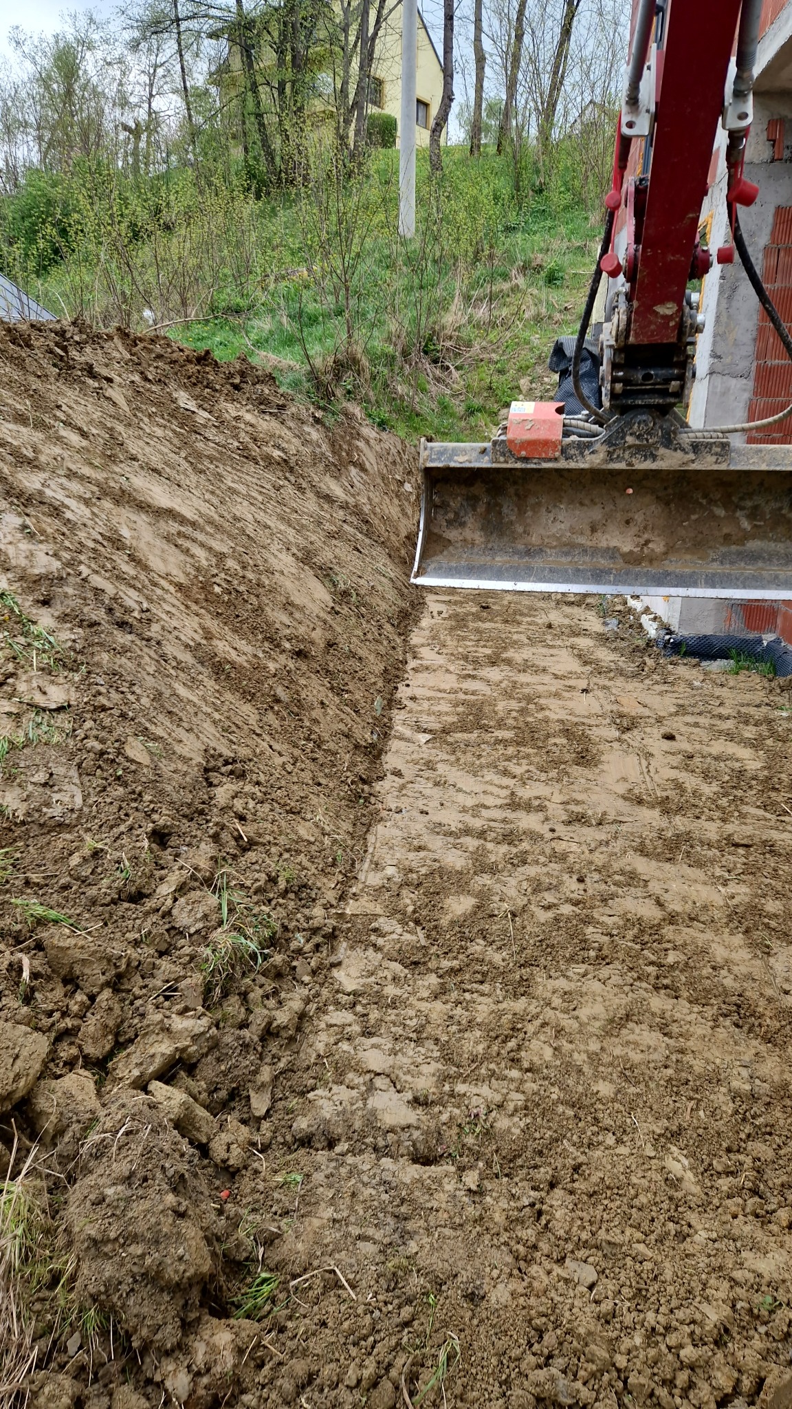 Częściowe ujęcie wykopu pod budynek w Nowym Sączu, widoczna krawędź wykopu, fragment fundamentu i łyżka koparki.