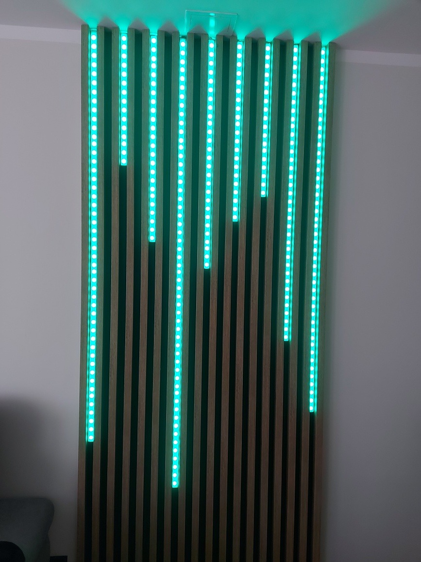 Dekoracyjna ściana z drewnianych listew z wbudowanym oświetleniem LED w kolorze turkusowym, tworząca efekt wizualny w nowoczesnym wnętrzu.