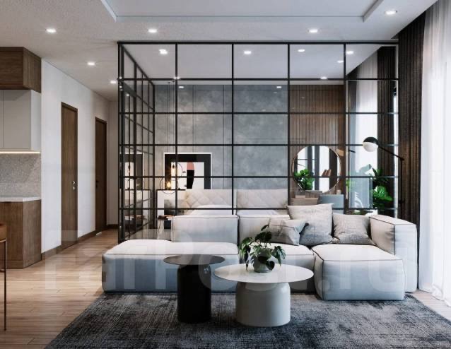 Nowoczesne wnętrze z przeszkleniem w czarnej ramie oddzielającym salon od sypialni, szara sofa modułowa, okrągły stolik kawowy na dywanie.