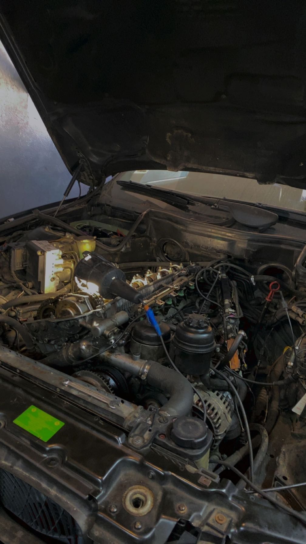 Otwarta maska samochodu w Lublinie, podświetlony lampą roboczą silnik podczas naprawy.