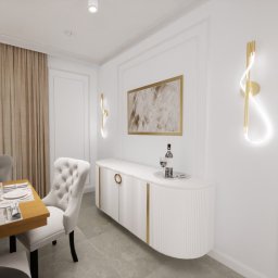 OMNIA DESIGN NATALIA ŁOŚ-MORGAŚ - Elegancka jadalnia w jasnych barwach z białym kredensem z dekoracyjnymi złotymi elementami, obrazem w złotej ramie i nowoczesnymi złotymi kinkietami. Stół z nakryciem i krzesłem w stylu glamour.