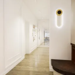 Nowoczesny korytarz z kominkiem i minimalistycznym oświetleniem ściennym, jasne drewniane podłogi i białe ściany z dekoracyjnymi listwami.