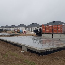 Błysk Śrem - Przygotowane fundamenty pod budowę osiedla domów jednorodzinnych; na jednym z fundamentów zaparkowana ciężarówka z materiałami budowlanymi - cegłami Termoton.