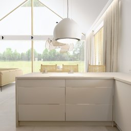 MATO PROJEKT pracownia projektowa - Jasna, minimalistyczna kuchnia z wyspą kuchenną, widok na salon i ogród przez duże okno z drewnianą ramą, designerska lampa wisząca i drewniane żaluzje.