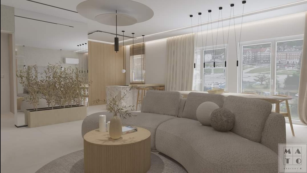 Wizualizacja salonu w jasnych, neutralnych barwach z zaokrągloną sofą, okrągłym stolikiem kawowym i roślinami w donicach, z widokiem na jadalnię i okna z widokiem na miasto.