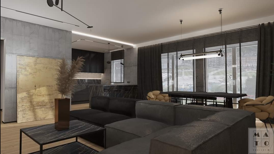 Nowoczesne wnętrze salonu z otwartą kuchnią, szara sofa modułowa, marmurowy stolik kawowy, złoty obraz na betonowej ścianie, czarne meble kuchenne z marmurowym blatem, okno z żaluzjami.