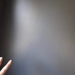 ykonczenia wnetrz maksym merhes - Świeżo pomalowana szara ściana z widocznymi palcami dłoni, na których widać ślady farby.