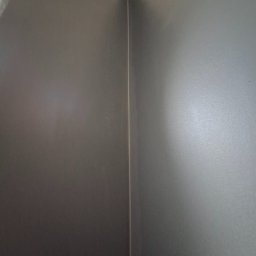 ykonczenia wnetrz maksym merhes - Szara ściana po szpachlowaniu i malowaniu, widoczny narożnik z delikatnym przejściem kolorystycznym pod różnym kątem padania światła.