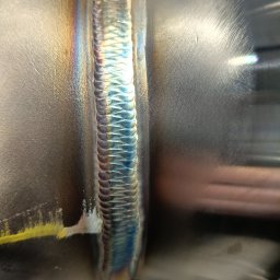 VitaliiViztech - Precyzyjne spawanie TIG rur ze stali nierdzewnej. Widoczna wysoka jakość spoiny z charakterystycznymi kolorami utleniania. Detal z bliska.