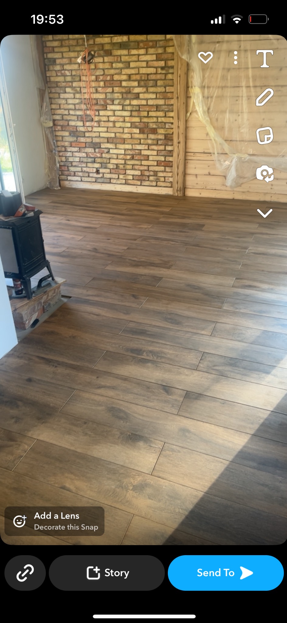 Ułożona podłoga z płytek imitujących drewno w surowym wnętrzu z ceglaną ścianą i zabezpieczonymi folią elementami drewnianymi.