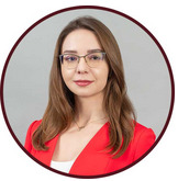 Portret kobiety w okularach, ubrana w czerwoną marynarkę, na neutralnym szarym tle.