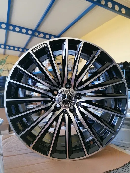 Aluminiowa felga Mercedes-Benz AMG z wieloramiennym wzorem, czarno-srebrna, eksponowana w warsztacie.