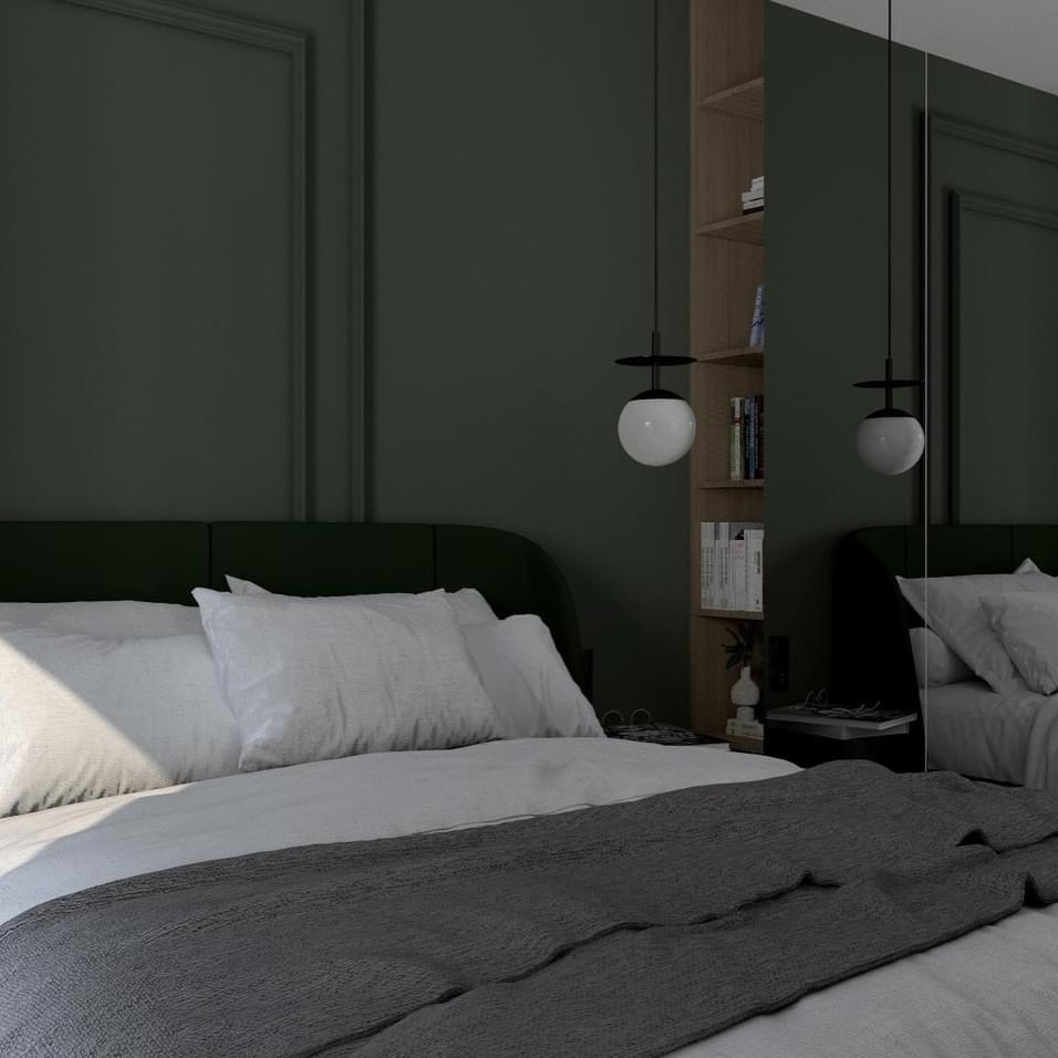 Nowoczesna sypialnia z ciemnozieloną ścianą, łóżkiem z zielonym zagłówkiem, białymi poduszkami i szarą narzutą, oświetlona wiszącą lampą kulą i odbijająca się w lustrze.
