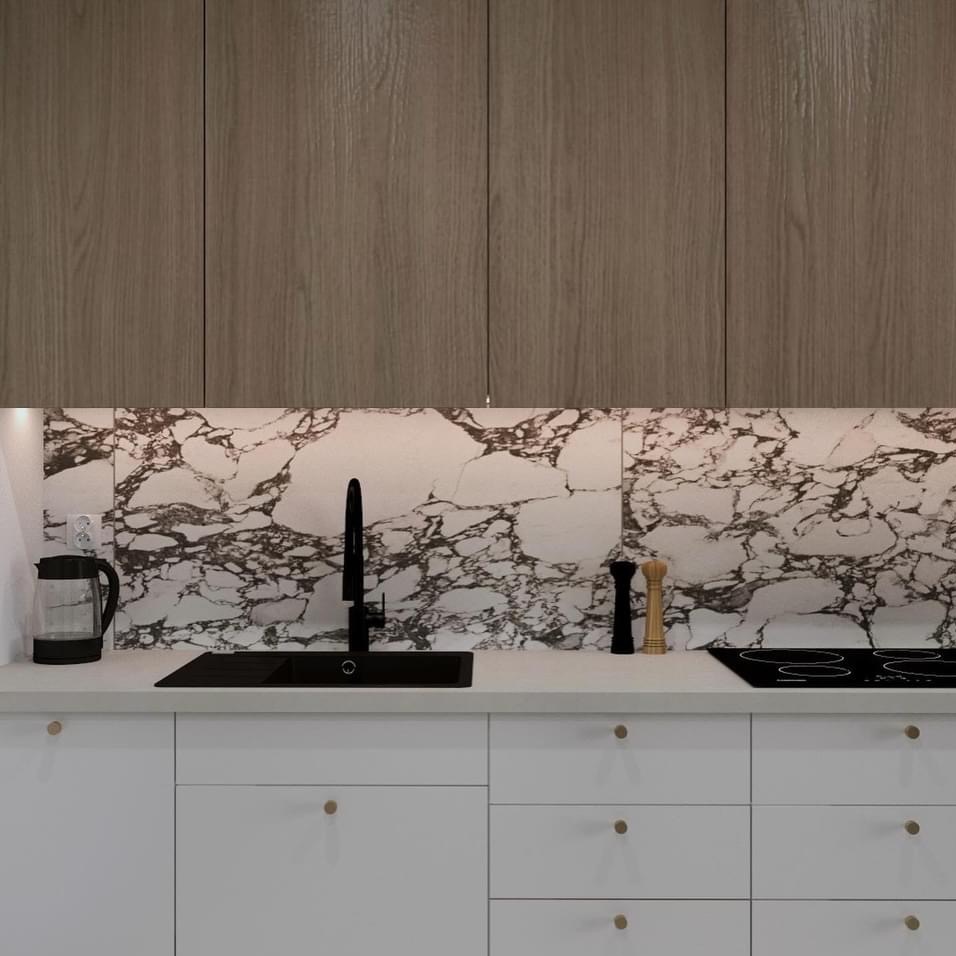 Nowoczesna kuchnia z białymi szafkami, drewnianymi górnymi szafkami i marmurowym backsplashiem, czarny zlew i bateria, czajnik elektryczny po lewej.