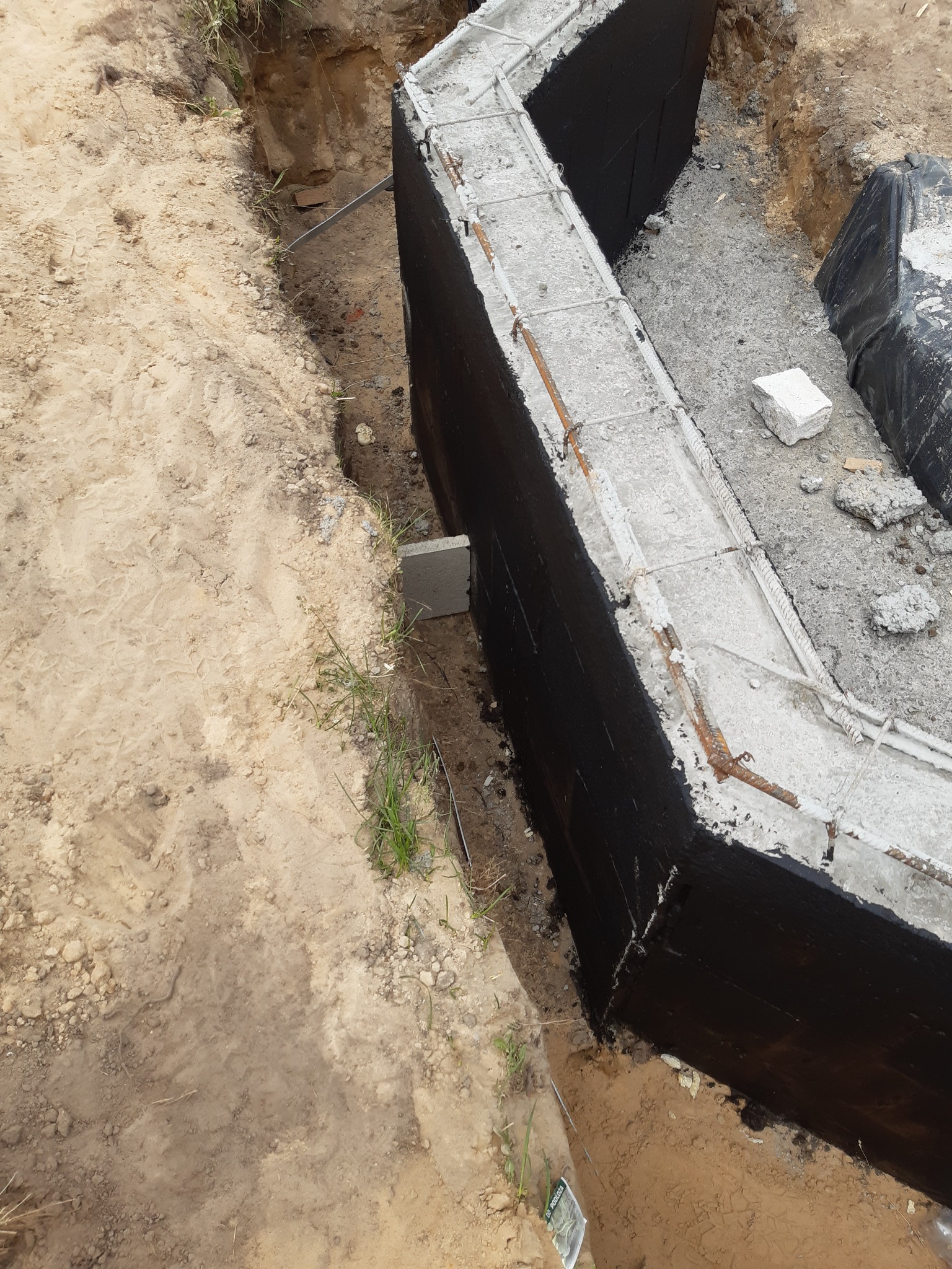 Wykop pod fundamenty z wykonaną hydroizolacją pionową ścian oraz zbrojenie z betonu w wykopie ziemnym.