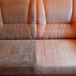 Czyszczenie tapicerki meblowej - Dwusiedziskowa kanapa z wyraźnym podziałem na część wyczyszczoną i zabrudzoną, ukazującą efekty usługi czyszczenia tapicerki.