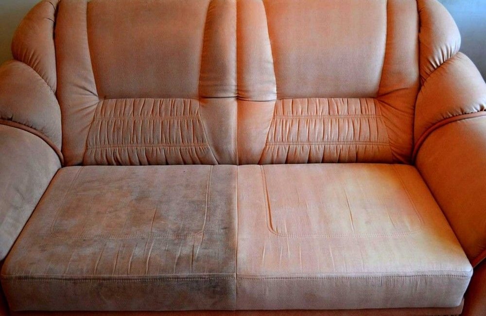 Dwusiedziskowa kanapa z wyraźnym podziałem na część wyczyszczoną i zabrudzoną, ukazującą efekty usługi czyszczenia tapicerki.