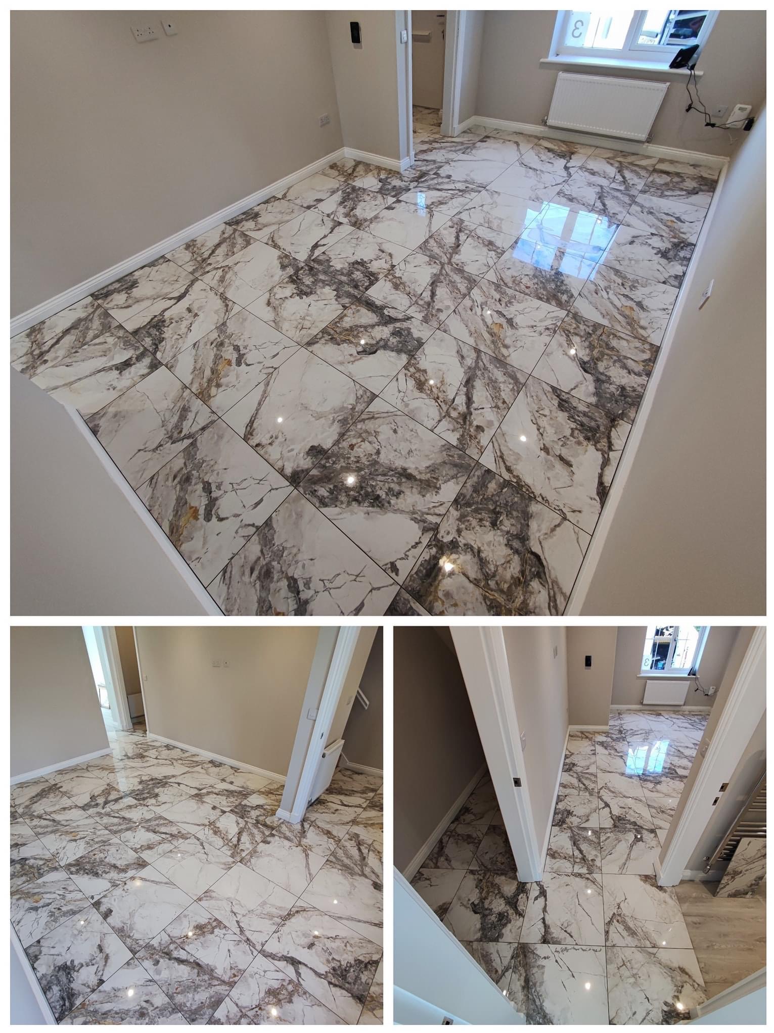 Podłoga wyłożona białymi płytkami imitującymi marmur z szarymi i złotymi żyłami, widok na fragment pomieszczenia z grzejnikiem pod oknem i otwartymi drzwiami do kolejnych pomieszczeń.