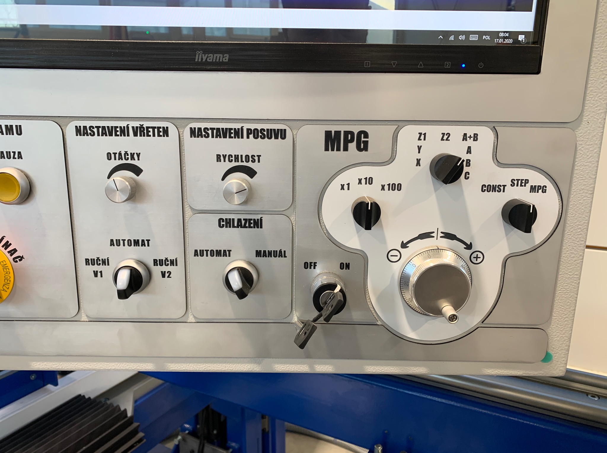 Panel sterowania maszyny CNC z przyciskami, pokrętłami i wyświetlaczem Iiyama, widoczne ustawienia obrotów, prędkości posuwu, chłodzenia oraz tryby pracy automatycznej i ręcznej.