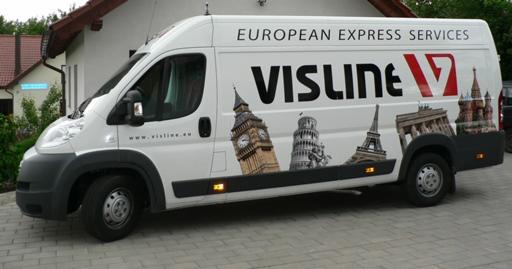Biały samochód dostawczy firmy Visline European Express Services z grafiką przedstawiającą Big Ben, Krzywą Wieżę w Pizie, Wieżę Eiffla i Bramę Brandenburską, zaparkowany na szarym bruku.