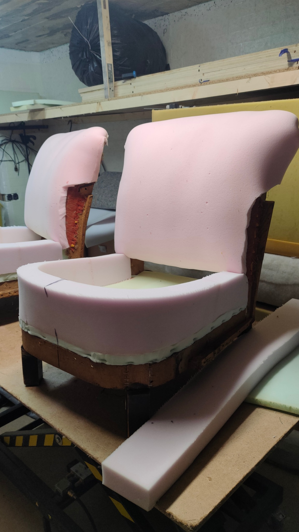 Dwa fotele w trakcie renowacji, z widoczną drewnianą konstrukcją i nową pianką tapicerską, ukazujące etap pracy przed ostatecznym obiciem materiałem.