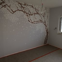 YA COMPANY SPÓŁKA Z OGRANICZONĄ ODPOWIEDZIALNOŚCIĄ - Ściana w pokoju w Warszawie z ręcznie malowanym motywem drzewa kwitnącej wiśni, widoczne puszki z farbą na parapecie okna.