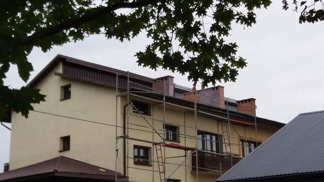 Budynek w trakcie prac na wysokości, widoczne rusztowania i częściowo odnowiona elewacja oraz nowy system orynnowania.
