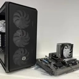 Otwarta obudowa komputera PC z trzema wentylatorami z przodu, obok płyta główna z zamontowanym chłodzeniem procesora na białym tle.