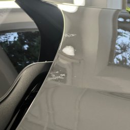 Yauheni Mardasevich - Szary lakier samochodu z widocznymi odpryskami i uszkodzeniami powłoki, widok z bliska na defekty.