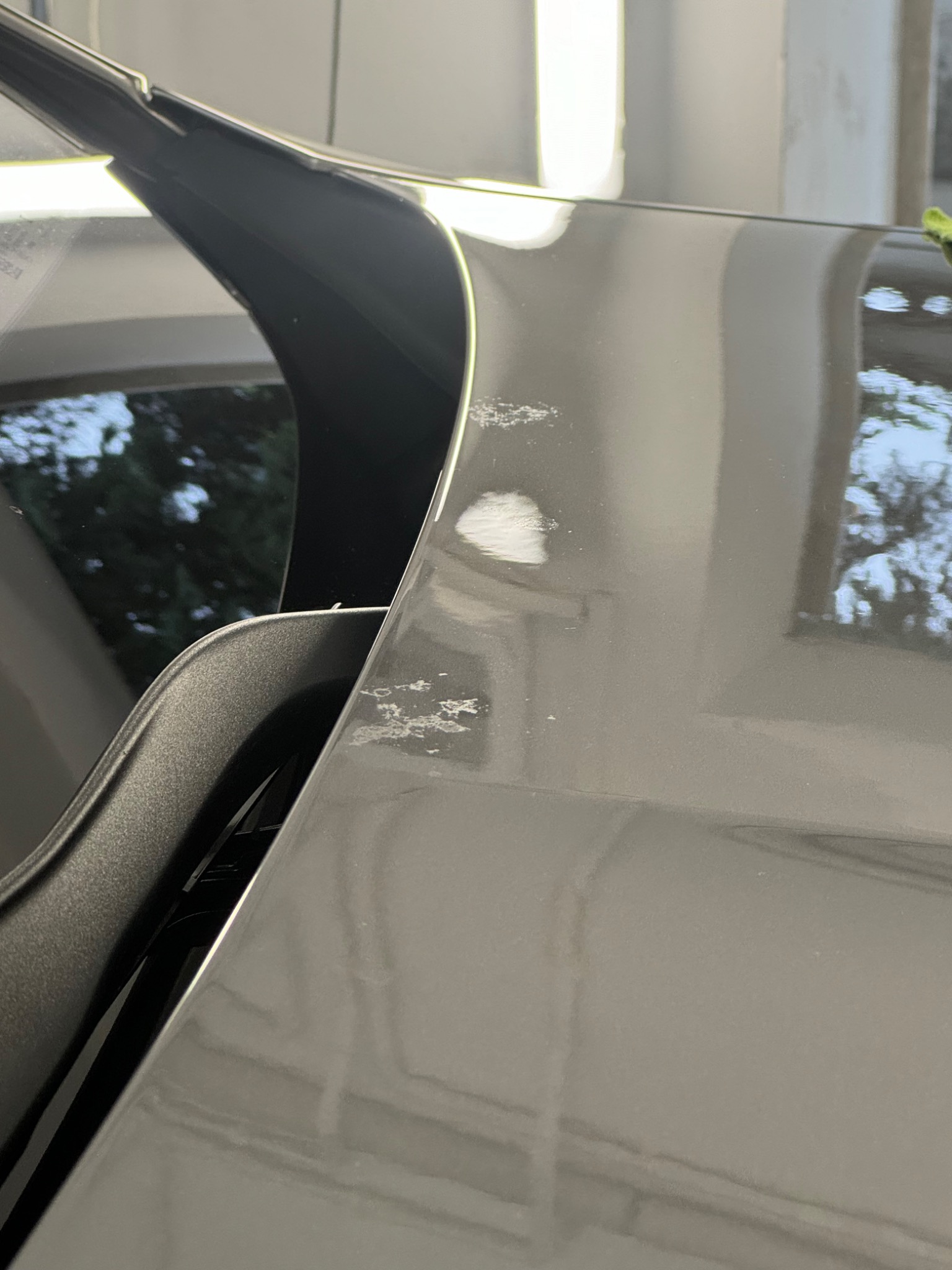 Szary lakier samochodu z widocznymi odpryskami i uszkodzeniami powłoki, widok z bliska na defekty.