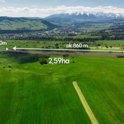 Artur Zając - Zdjęcie z lotu ptaka przedstawia rozległą, zieloną działkę zarysowaną fioletową linią, z podanymi wymiarami: ok. 400m, ok. 860m, ok. 23-30m oraz powierzchnią 2.59ha; w tle widoczne pasmo górskie...