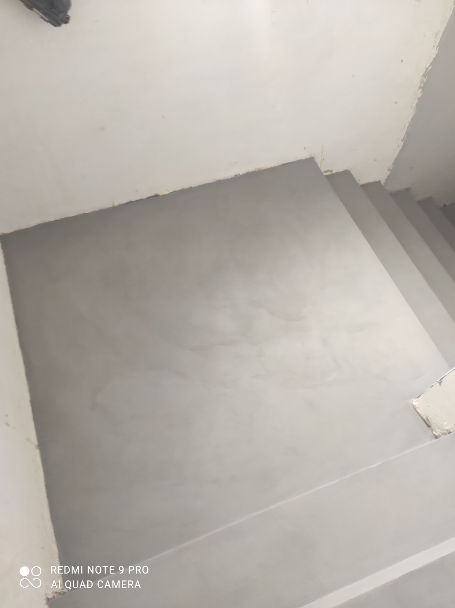 Szare wykończenie schodów i podłogi w pomieszczeniu, z bliska, z widoczną fakturą powierzchni. Neutralna kolorystyka i minimalistyczny design.