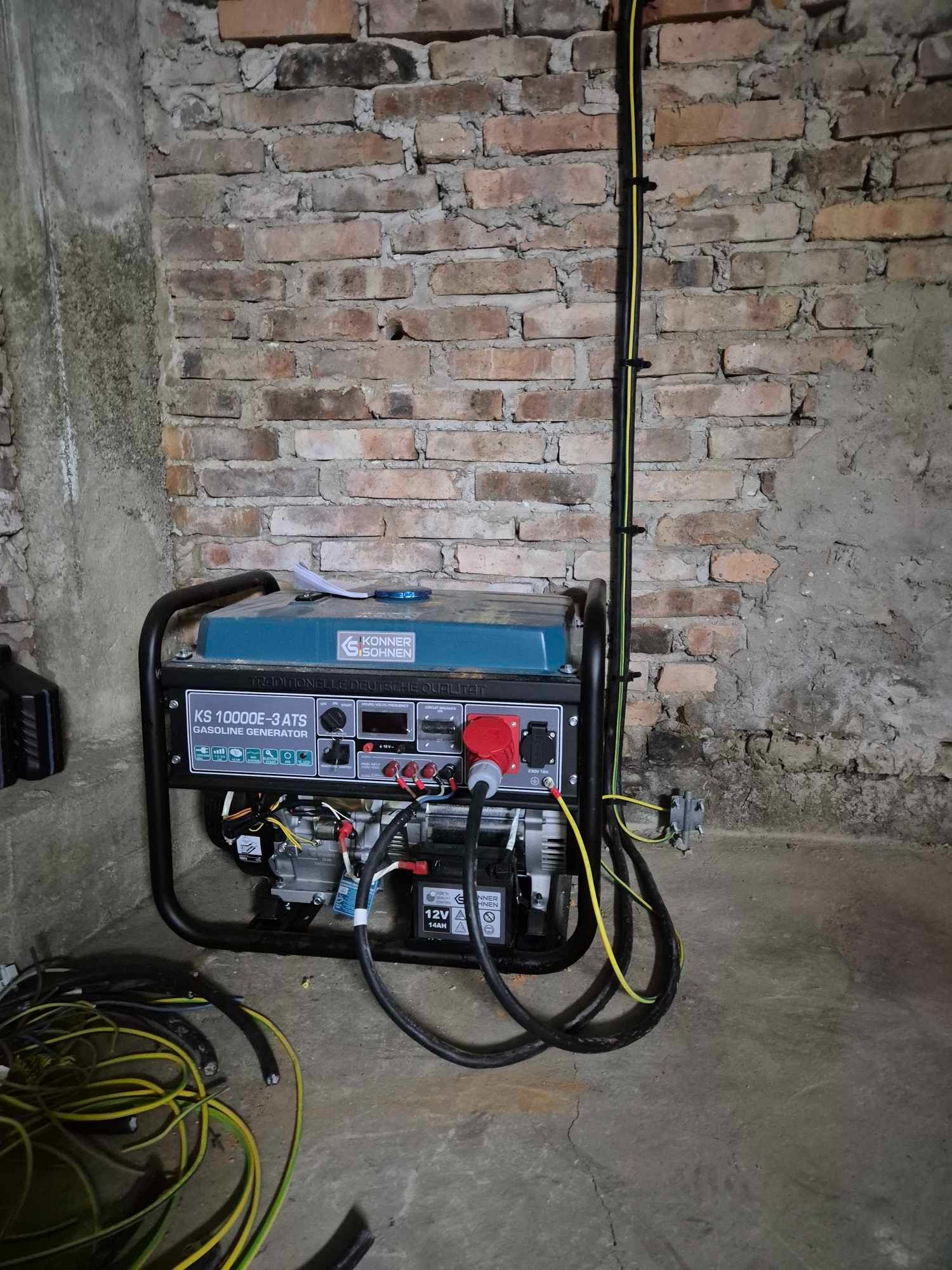 Agregat prądotwórczy spalinowy marki Konner & Sohnen KS 10000E-3 ATS ustawiony w piwnicy z widocznymi kablami elektrycznymi i puszką na ścianie z cegły.