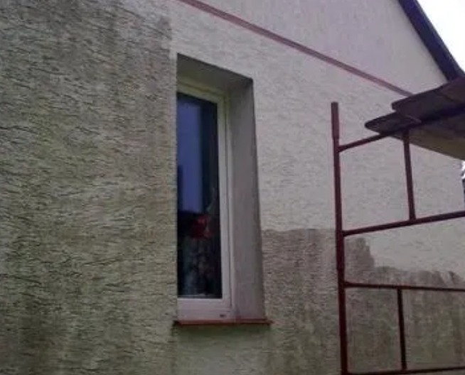 Fragment elewacji budynku z widocznym oknem i rusztowaniem, ślady niedawno wykonanych prac na ścianie, widoczna różnica w kolorze i fakturze.