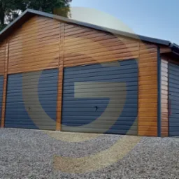 Drewniany garaż z trzema szarymi bramami segmentowymi, widok z zewnątrz na żwirowym podłożu, fragment srebrnego samochodu w kadrze.