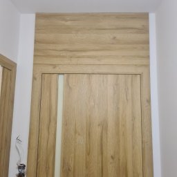 MPSMONT PIOTR KOZAKIEWICZ - Zamknięte, drewniane drzwi wewnętrzne z mleczną szybą, dopasowane do obudowy nadproża. Po lewej widoczna instalacja elektryczna przed wykończeniem.