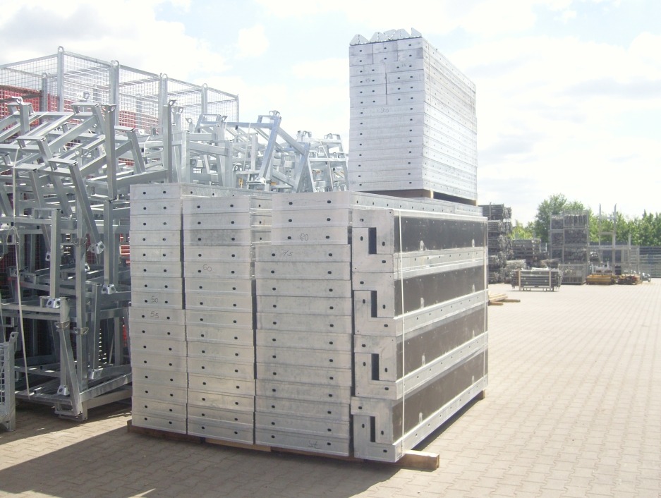 Sztaple szalunków stalowych na placu budowy, widoczne elementy rusztowań i palety