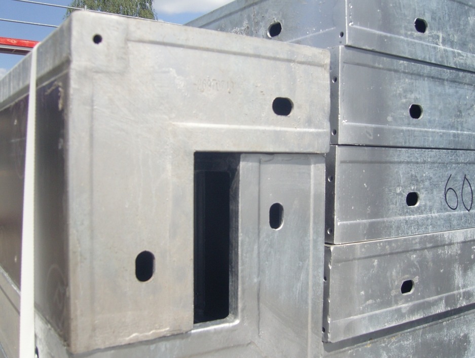 Stos metalowych szalunków budowlanych z widocznymi otworami i numerem '60' napisanym markerem na jednym z elementów.