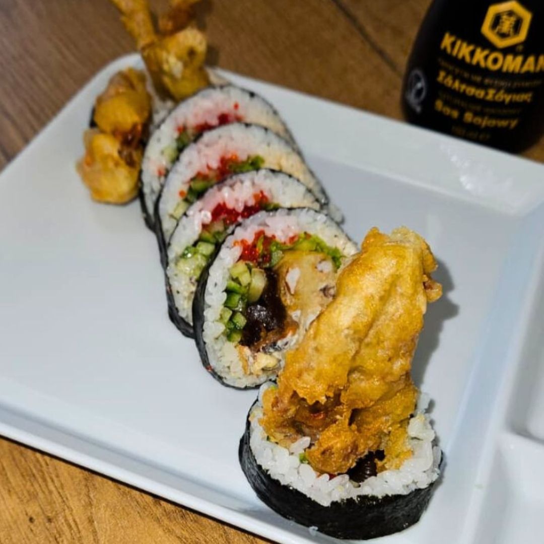 Sushi z tempurą i warzywami na białym talerzu, butelka sosu sojowego Kikkoman w tle.