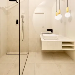 Nowoczesna łazienka w beżach z kabiną prysznicową typu walk-in z czarnymi detalami, umywalką nablatową i okrągłym lustrem podświetlonym wiszącymi lampami.