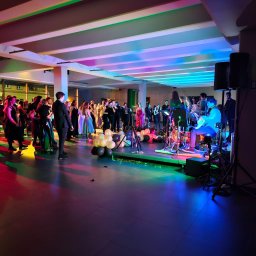 George Studio Kreatywne - Sala balowa z zespołem muzycznym na scenie, tancerze i goście w tle, dekoracja balonowa w odcieniach bieli i czerni, oświetlenie sceniczne w kolorach tęczy.