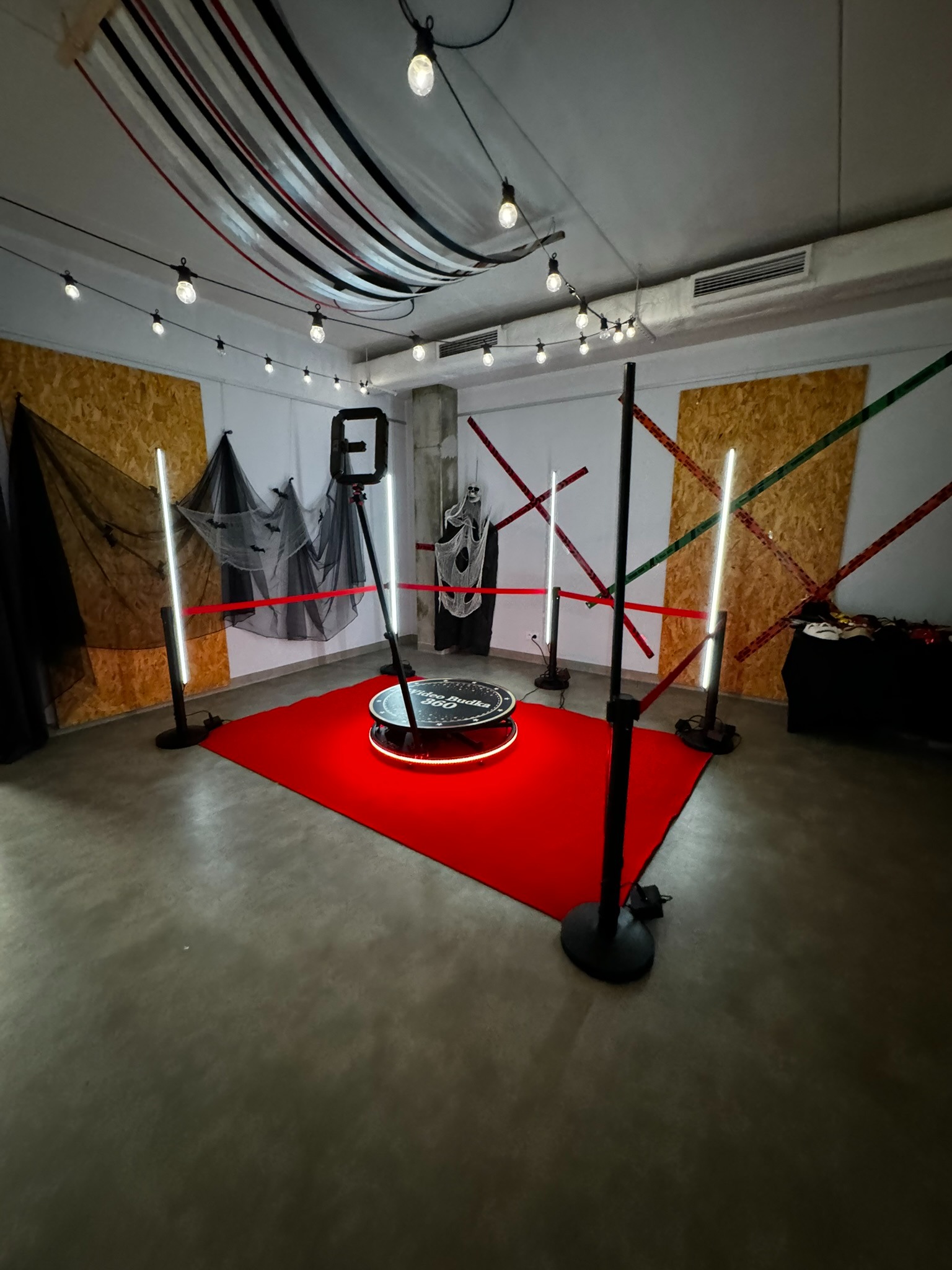 Przygotowana przestrzeń z obrotową platformą do nagrywania wideo, oświetleniem led i dekoracjami w stylu Halloween. Czerwony dywan, girlandy świetlne.
