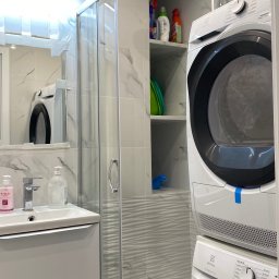 Perfectfix Remont - Nowoczesna łazienka po remoncie: kabina prysznicowa z marmurowymi płytkami, umywalka z szafką i pralka z suszarką Electrolux w zabudowie. Minimalistyczny design.